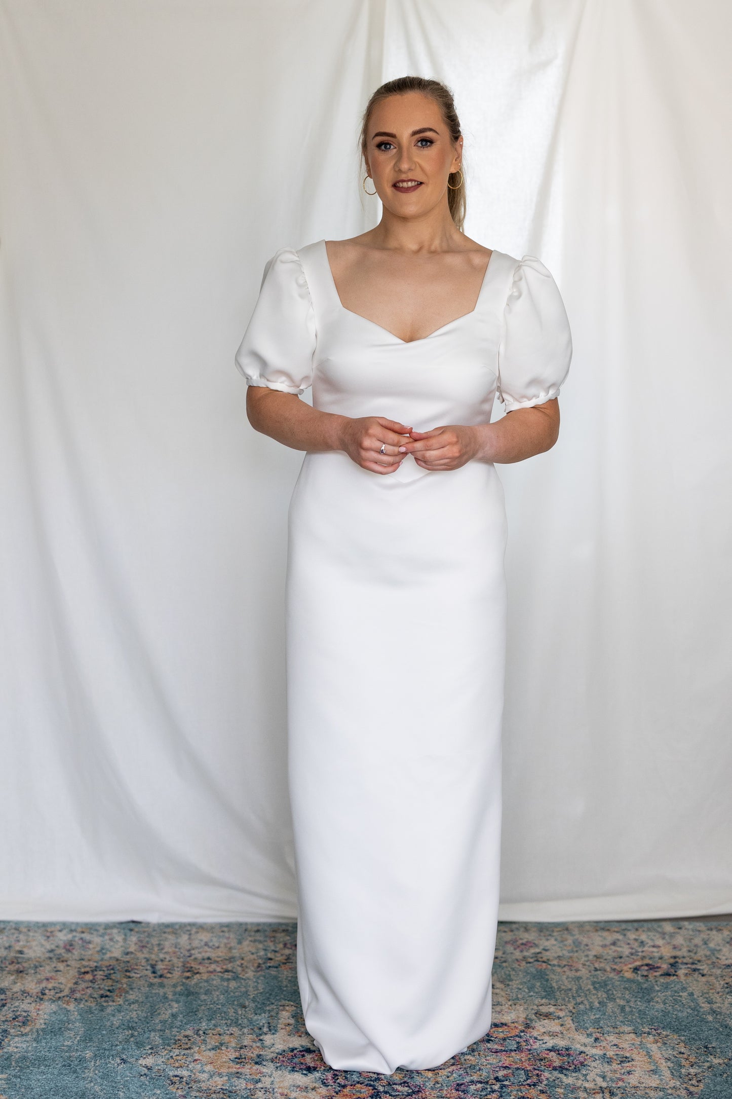 Minimalist white wedding gown with basque waistline and statement puff sleeves — modern column silhouette handcrafted by Mizz Rio in Ireland 