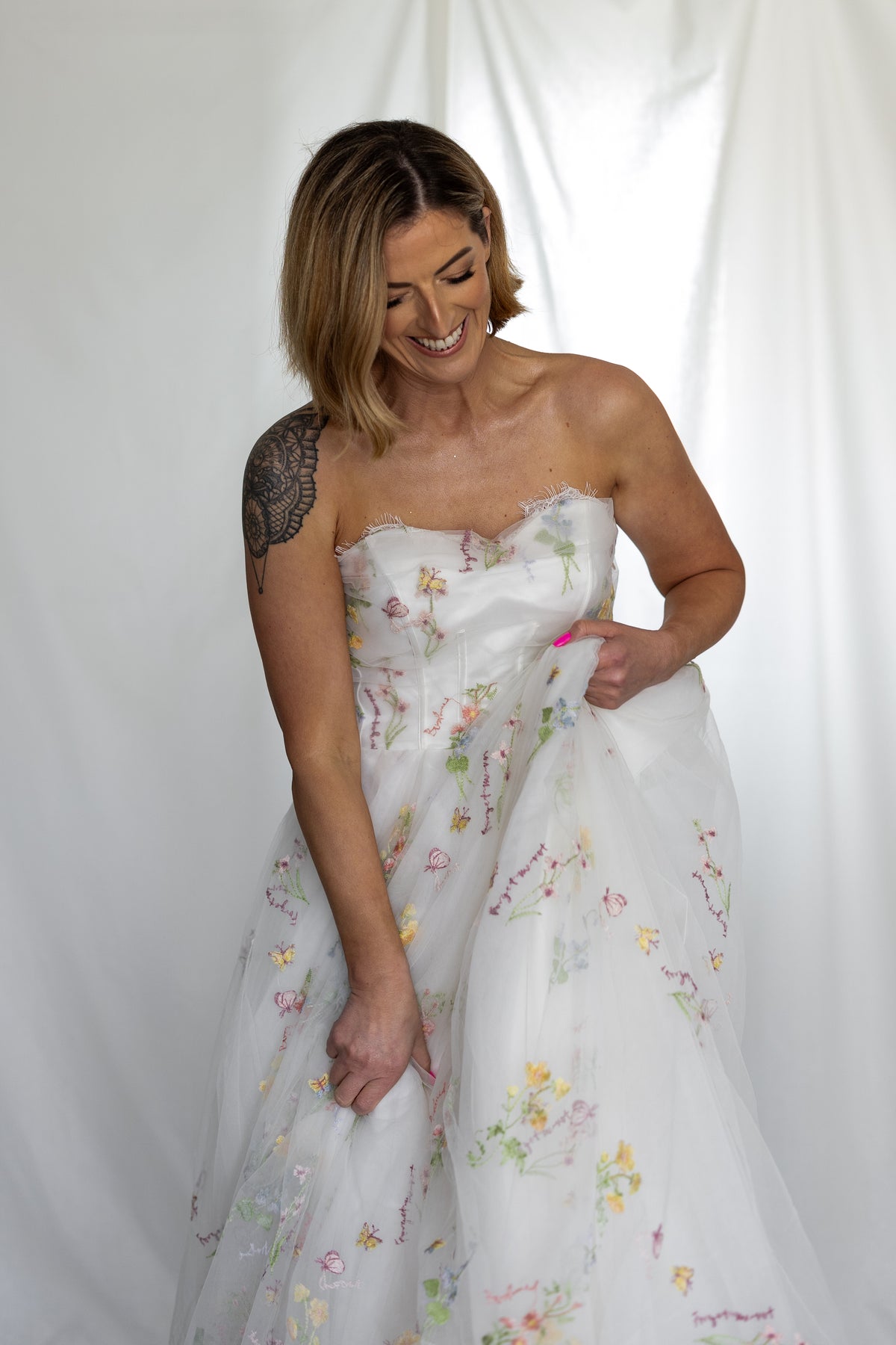 Smiling bride in the Forget-me-not strapless ivory tulle gown with pastel embroidered flowers – Mizz Rio floral wedding dress