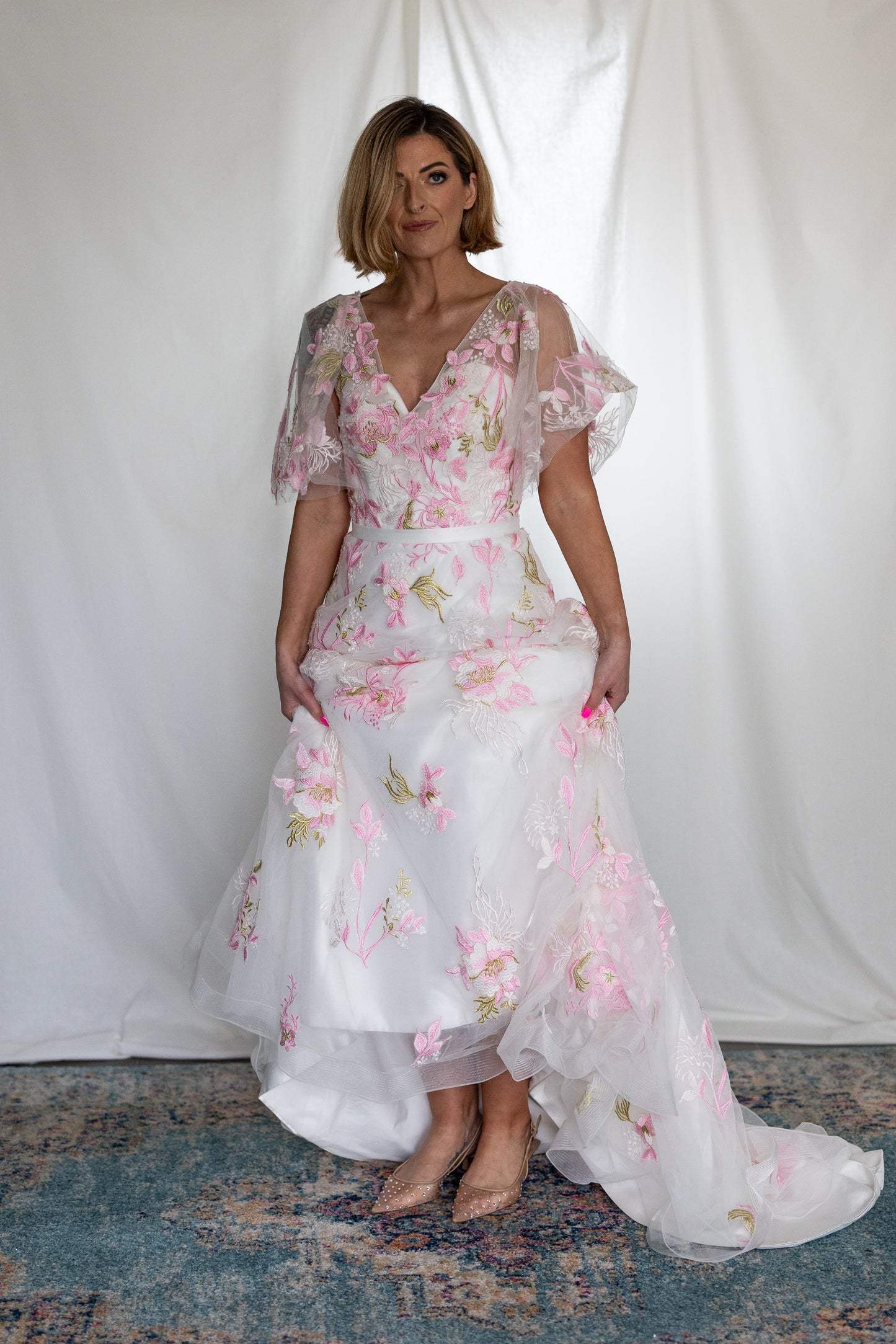 Pink floral embroidered wedding dress with sheer flutter sleeves and layered tulle skirt — modern romantic alternative bridal gown by Mizz Rio in Ireland 