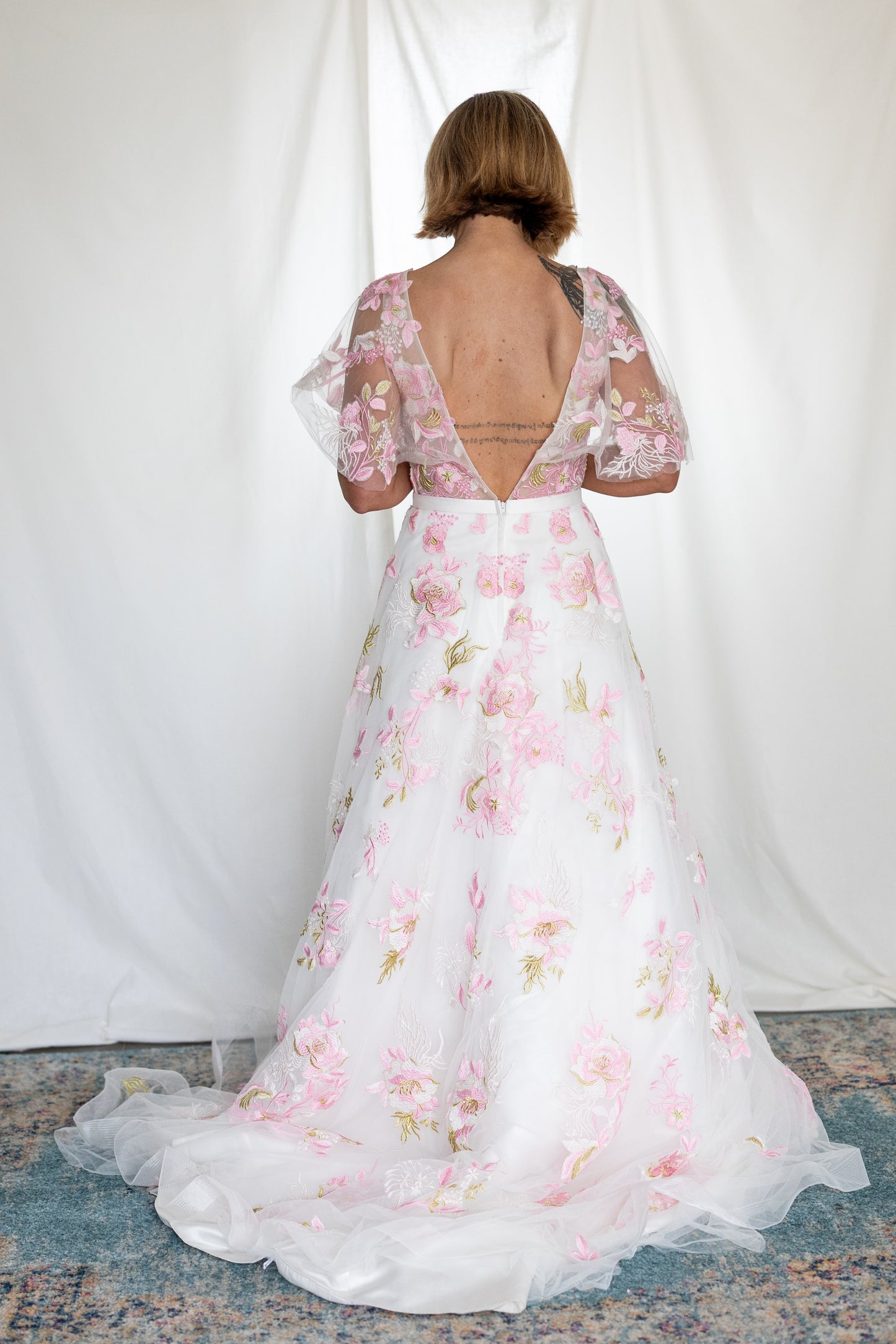 Pink floral embroidered wedding dress with sheer flutter sleeves and layered tulle skirt — modern romantic alternative bridal gown by Mizz Rio in Ireland 