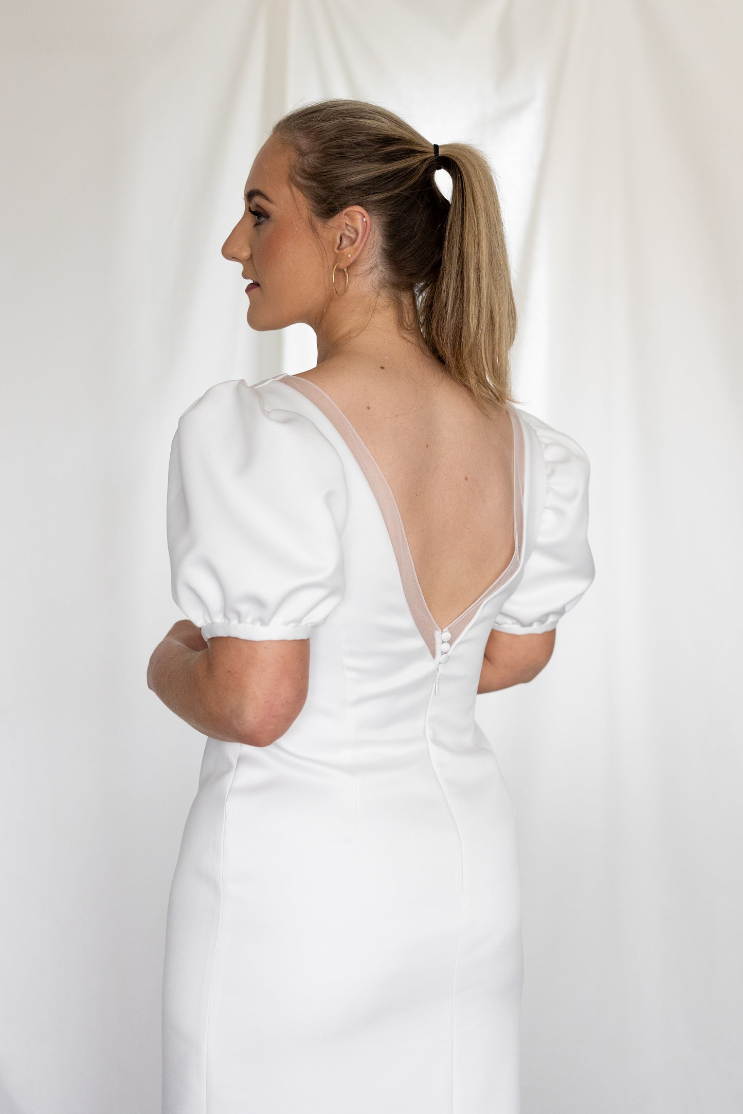 Minimalist white wedding gown with basque waistline and statement puff sleeves — modern column silhouette handcrafted by Mizz Rio in Ireland 