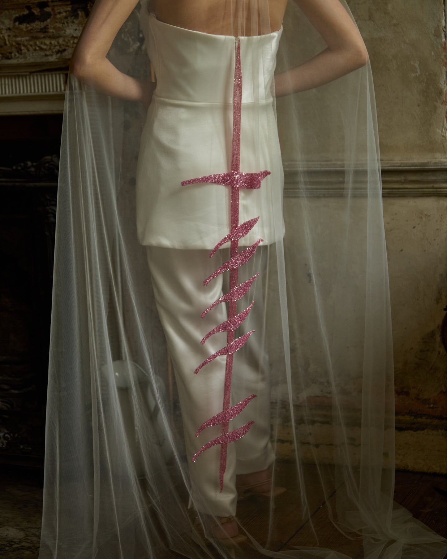 Modern bride in ivory mini dress and trousers wearing sheer tulle couture bridal veil with vertical pink sequin bra motif by Mizz Rio, alternative wedding look in Dublin