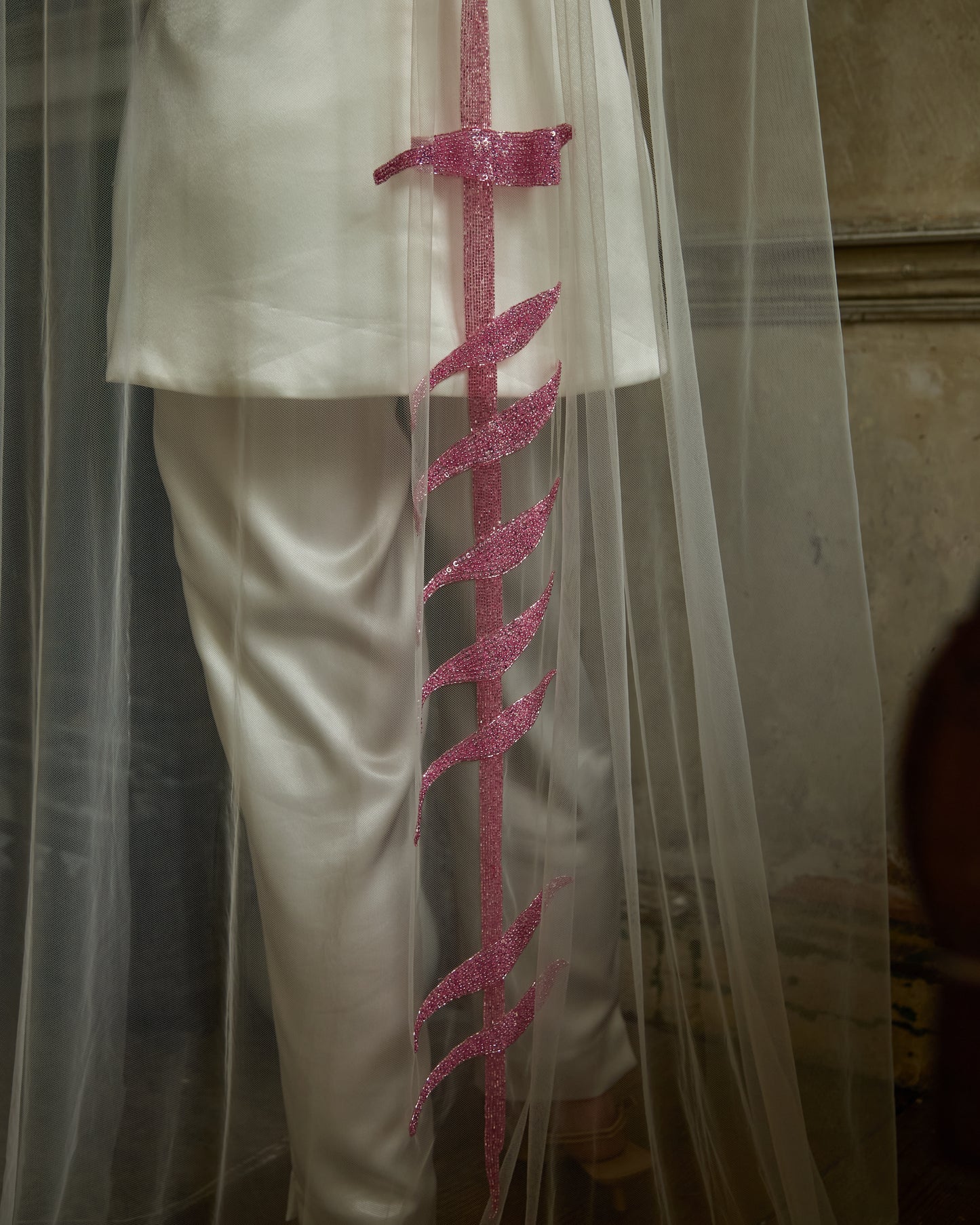 Modern bride in ivory mini dress and trousers wearing sheer tulle couture bridal veil with vertical pink sequin bra motif by Mizz Rio, alternative wedding look in Dublin