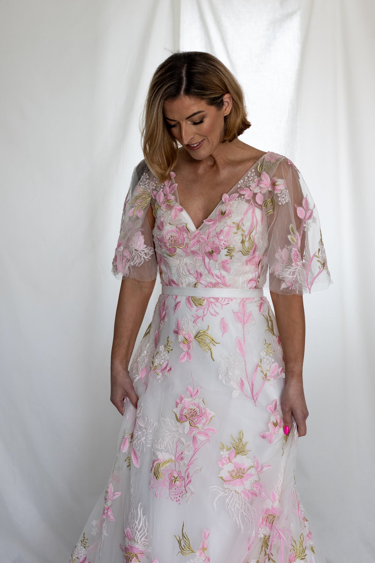 Pink floral embroidered wedding dress with sheer flutter sleeves and layered tulle skirt — modern romantic alternative bridal gown by Mizz Rio in Ireland 